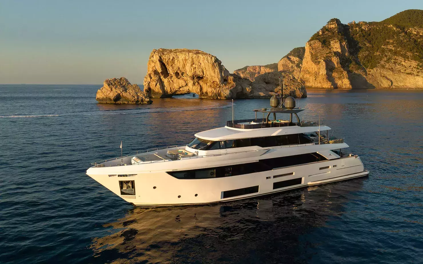 Luxury yacht anchored at sunset near Es Vedrà island